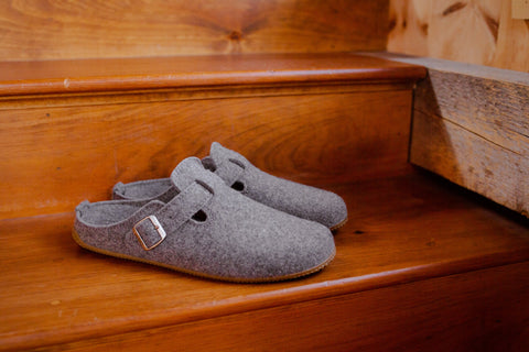 Pair of grey slippers on wooden stairs